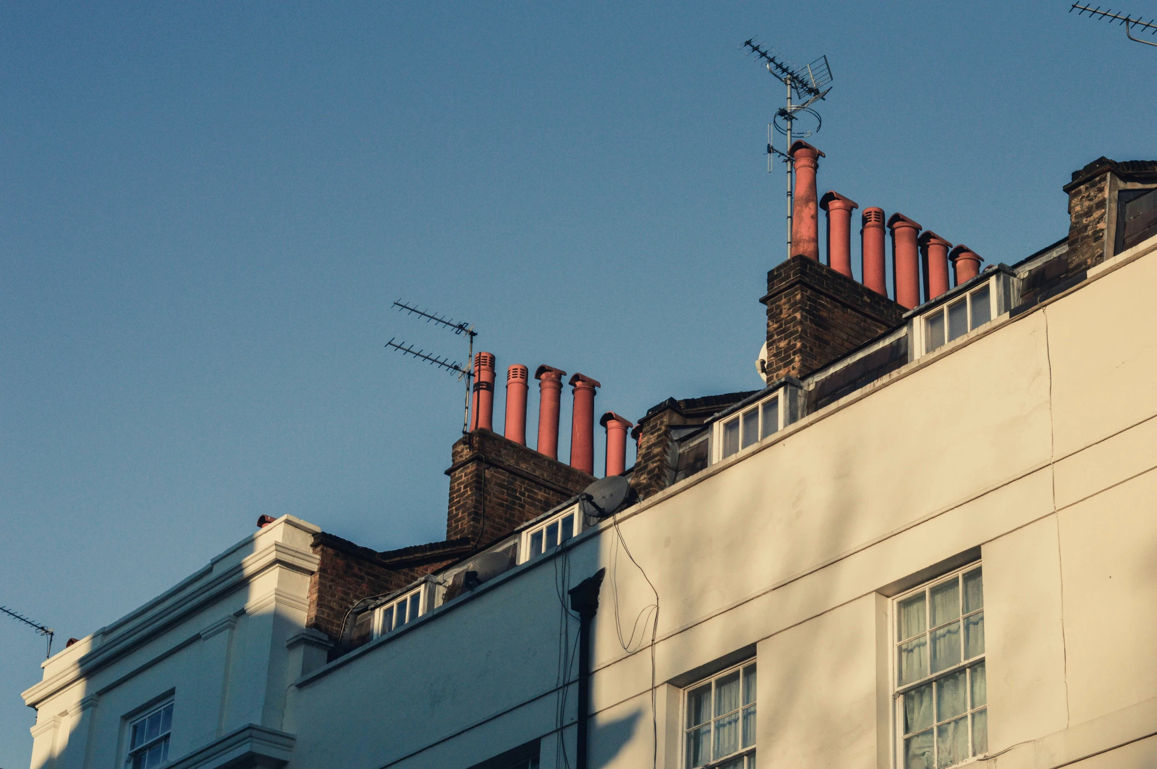 the top part of a row of building with chimneys