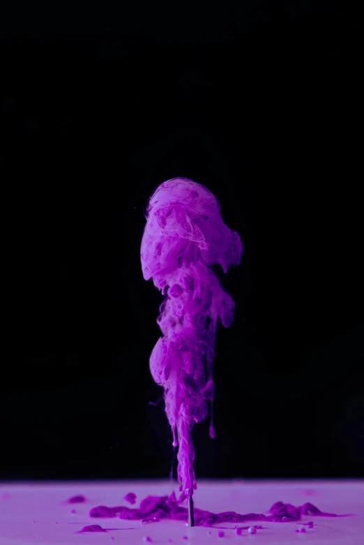 a purple liquid spewing from the top of a spoon