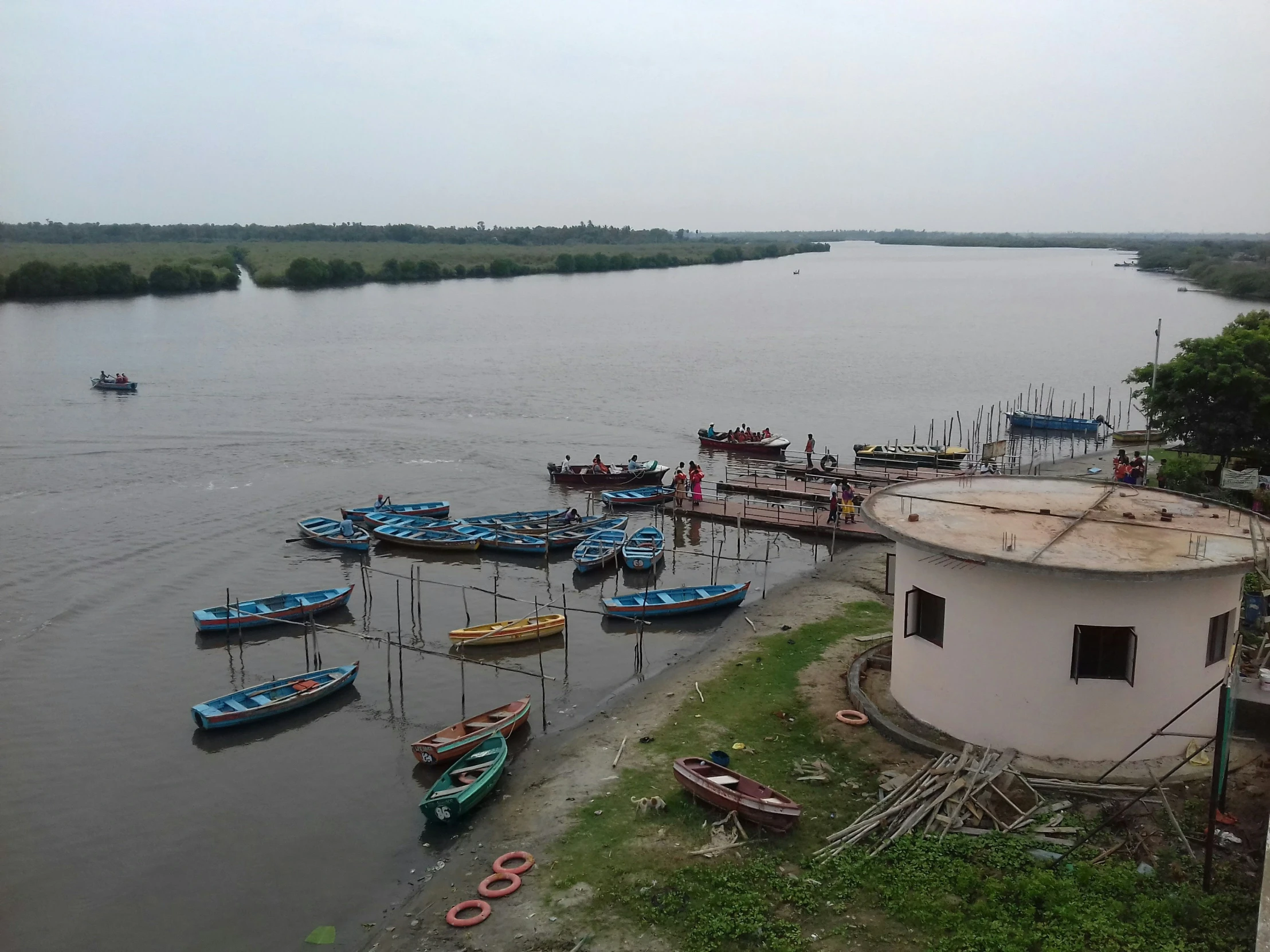 many boats are parked near the dock with people out in the water