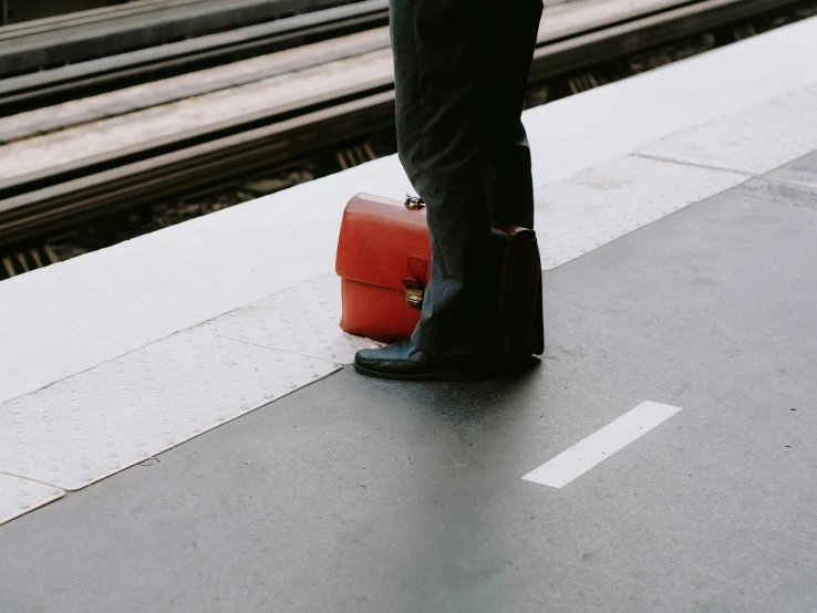 a person with a suitcase stands by a railway station platform