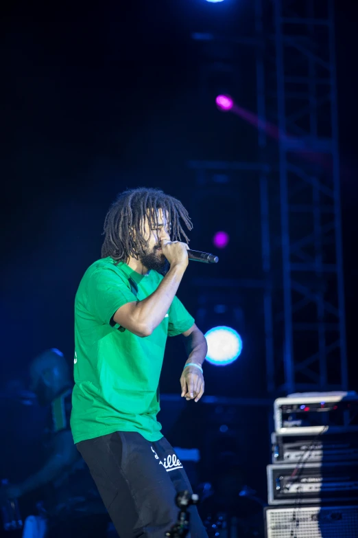 a man with dread locks on his neck singing at an outdoor concert