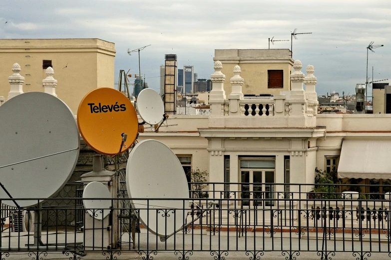 some antennas that are on the fence by a building