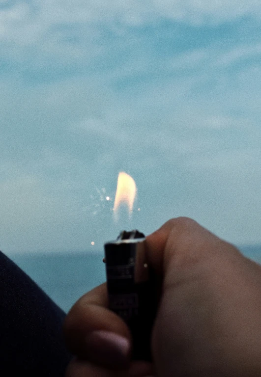 a hand holding a lighter that is almost lit