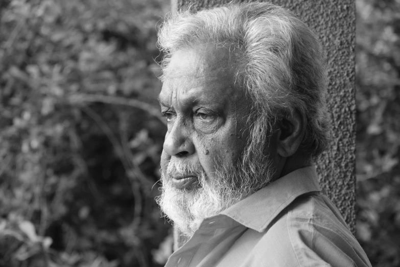 a man with a beard is leaning against a tree