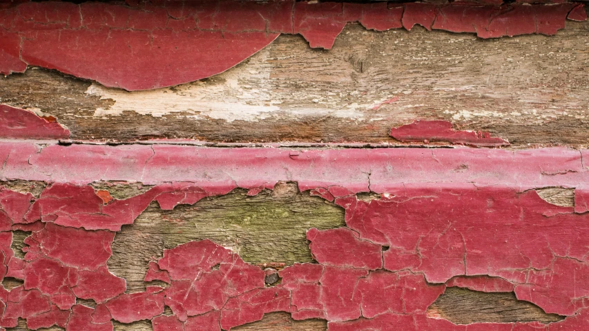 red paint is peeling and chipped off of an old wall