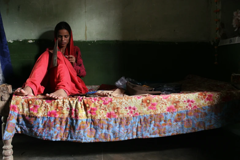 a girl sits on a bed talking on her phone