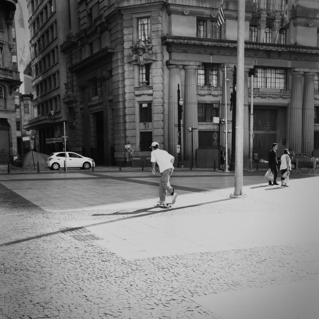 black and white pograph of a person skate boarding down the street