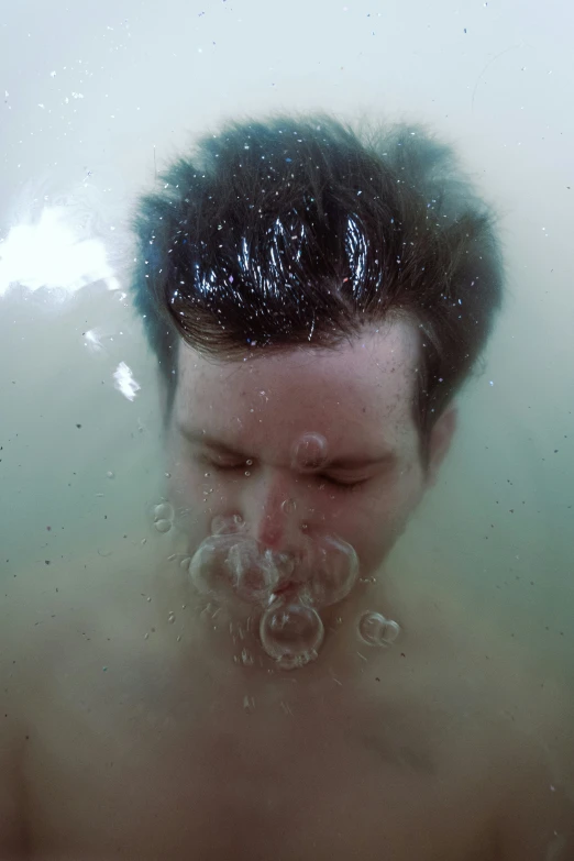 the head of a man in the water with bubbles around his