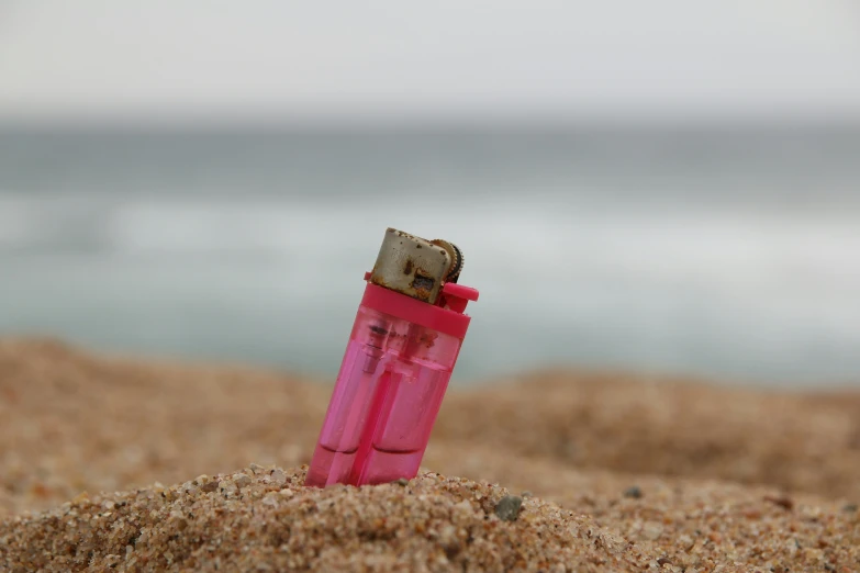 a lighter stuck in the sand near a body of water