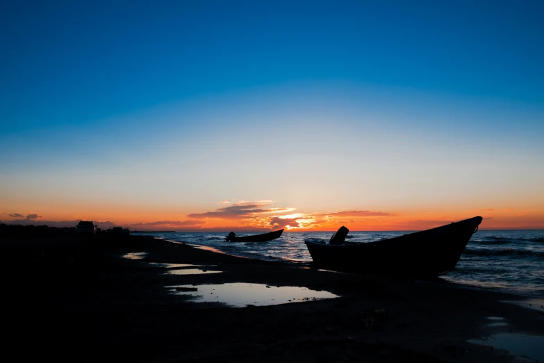 two canoes sitting on a beach in the sunset