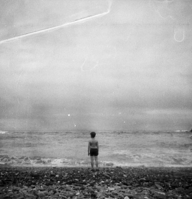 a young person watches the kite over the ocean