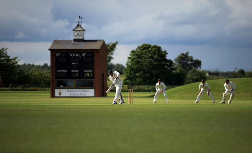 some men playing a game of cricket in front of the building