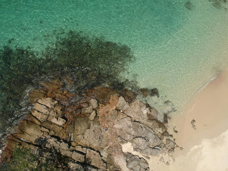 an overhead view of a body of water with a rocky shoreline and sandy beach