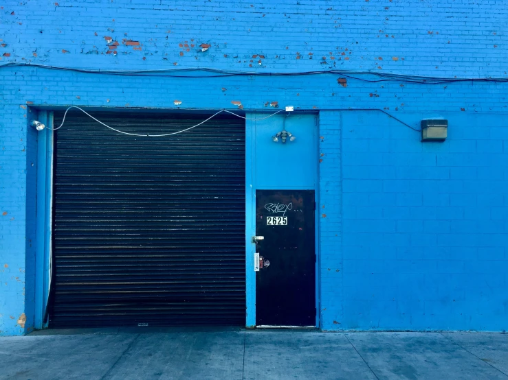 a black garage door next to a blue wall