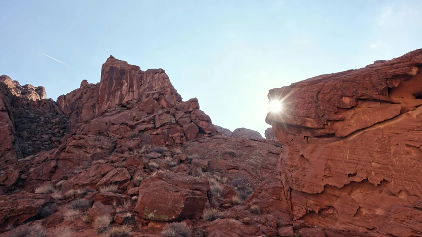 the sun shines brightly behind some red rocks