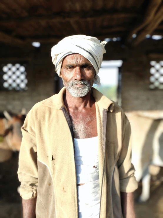 the man with a white turban is standing in front of some cows