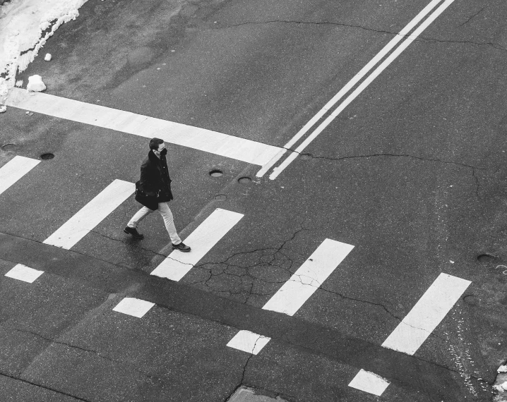 a man crossing a street holding his skateboard in one hand