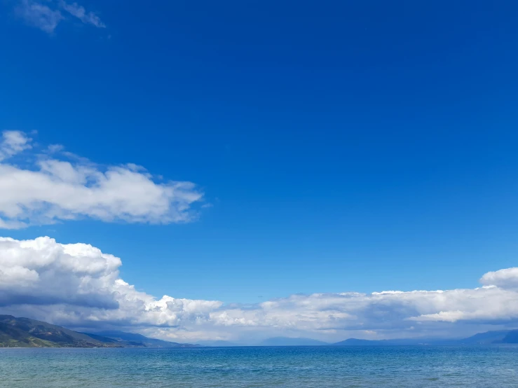 boat in blue water on the beach with mountains in the background