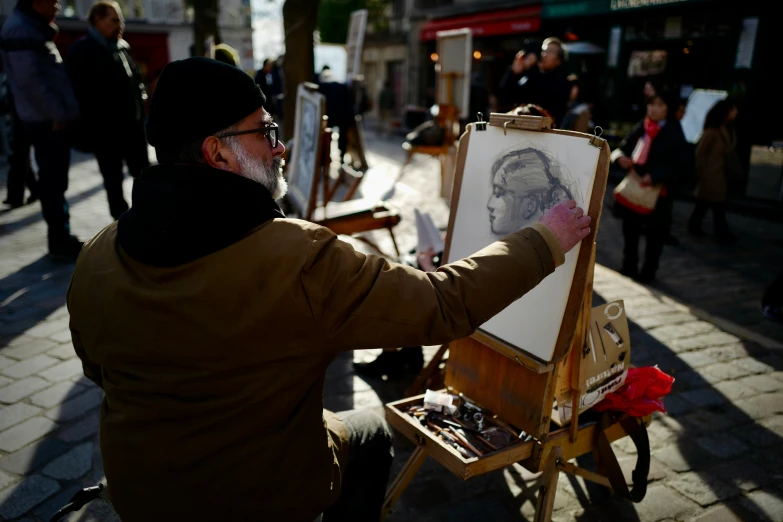 a man holding a white painting on top of a wooden easel