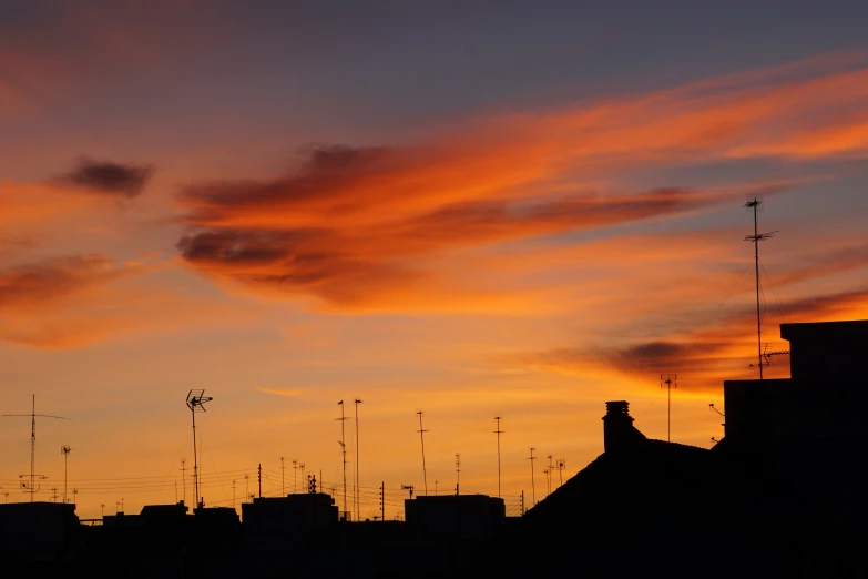 an orange and yellow sunset with some rooftops