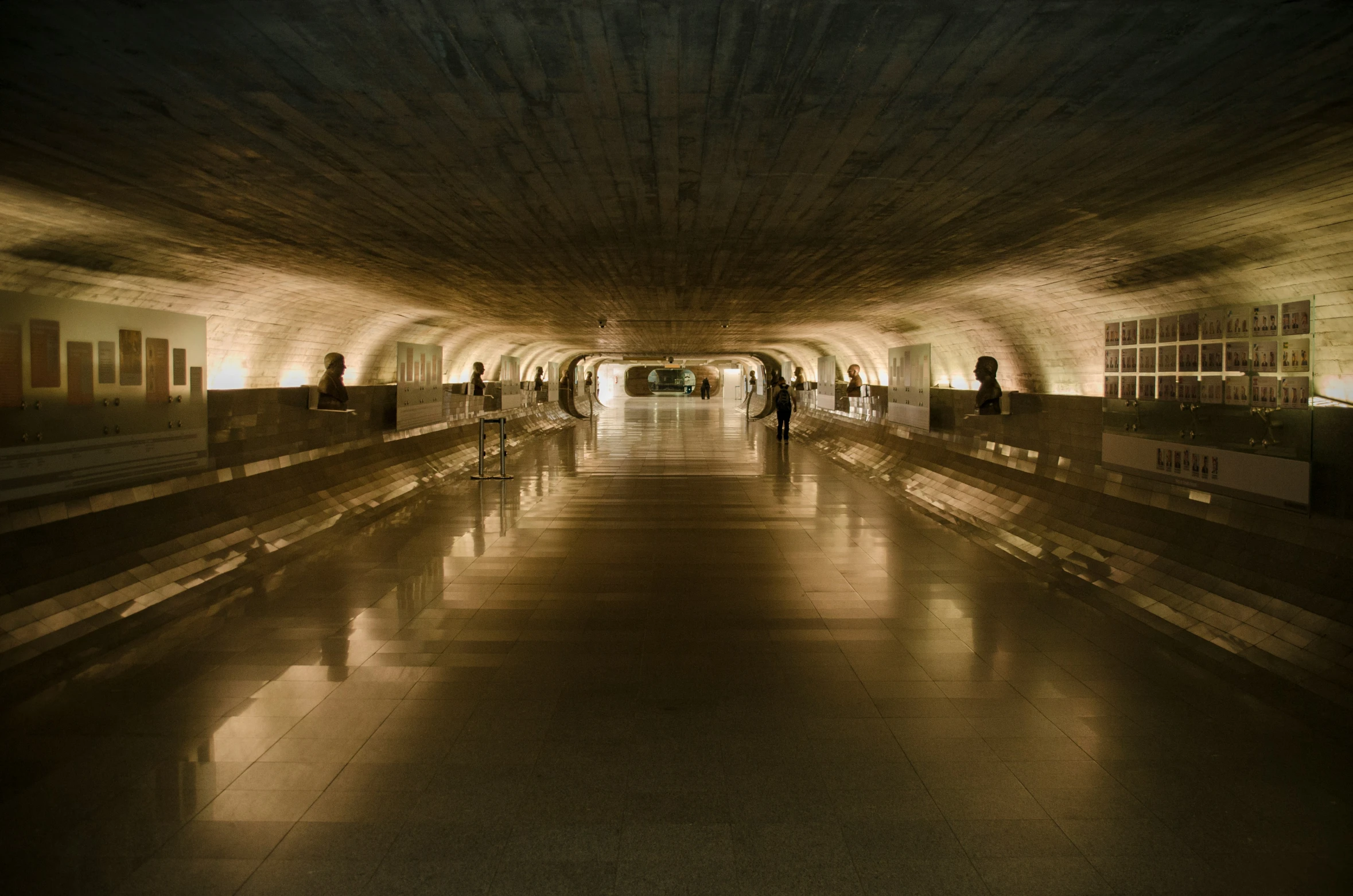 a long dark hallway leading into a small subway station