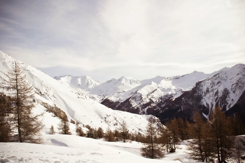 a snowy mountain landscape and the tops of mountains are obscured by clouds