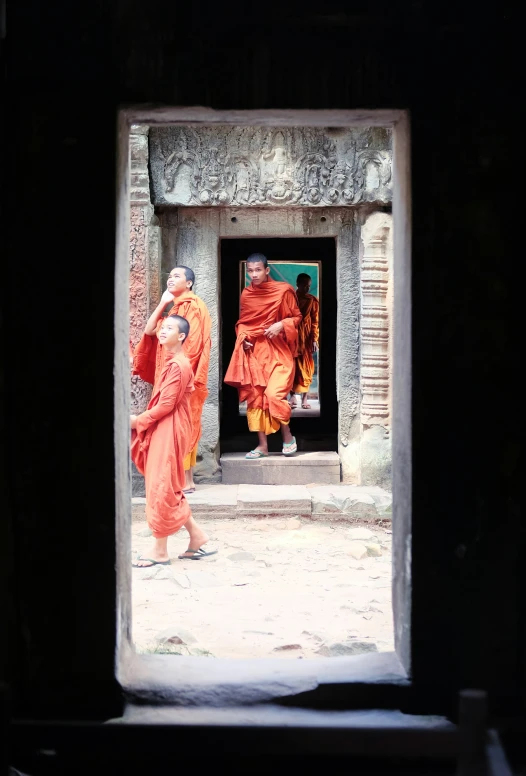 monks in orange robes in a doorway of an ancient temple