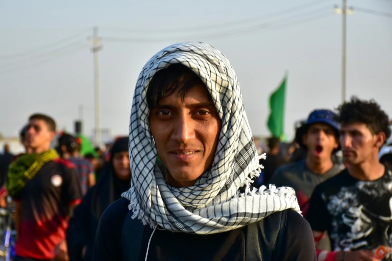 a guy wearing a gray and black sweater a scarf and some other people