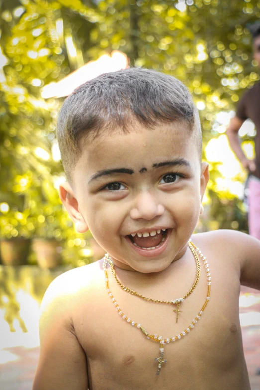 a child is wearing a gold necklace and a white bead