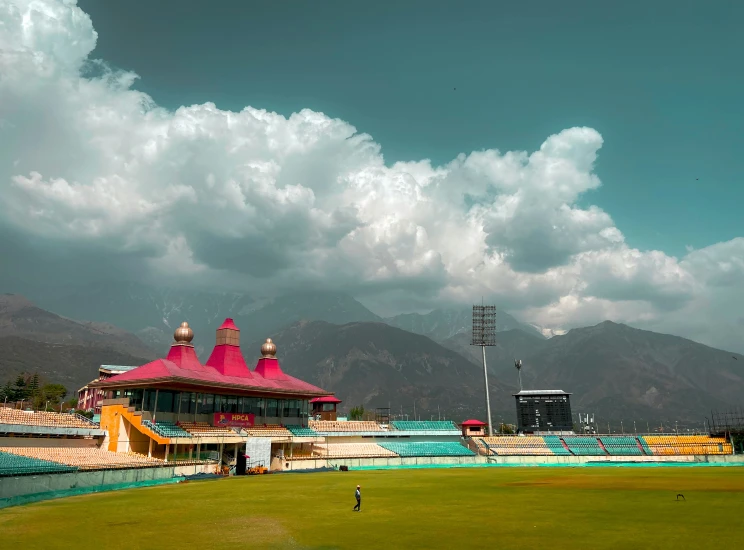 a large stadium with a baseball field, grass and mountains