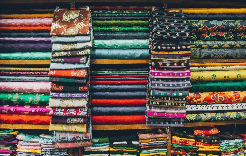 a rack full of brightly colored fabrics sitting on display