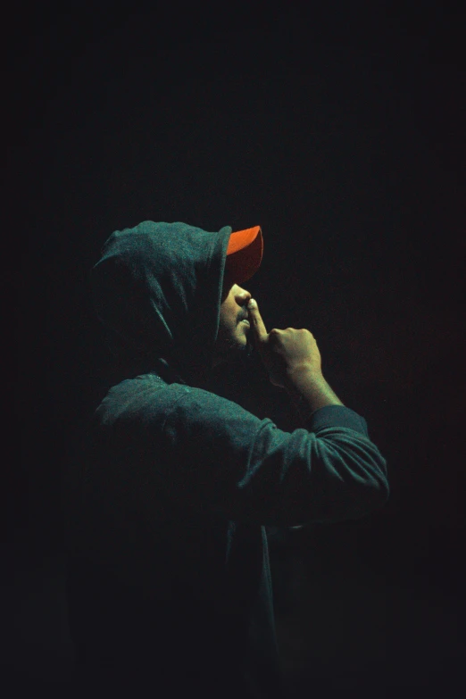 a man in a hoodie is smoking a cigarette