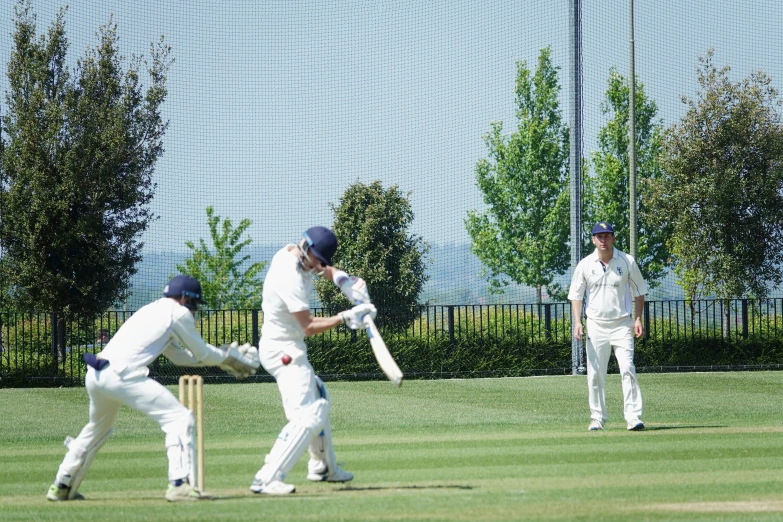 two men wearing white playing a game of cricket