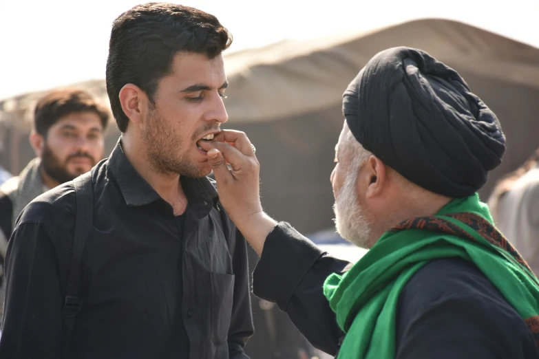 a man with an odd look brushing his teeth while looking at another man