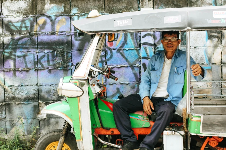 an older person on a motorbike with graffiti on the wall