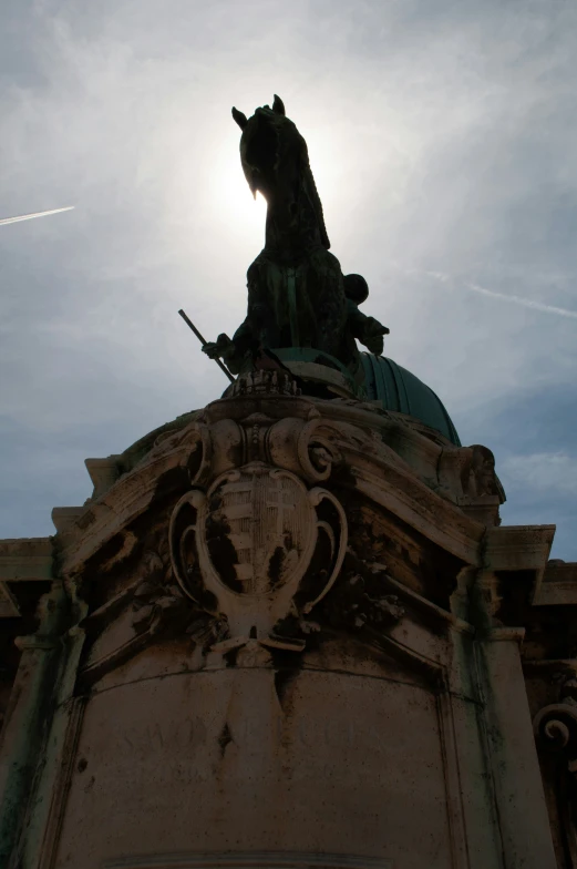 the sun is shining behind a statue on top of a building