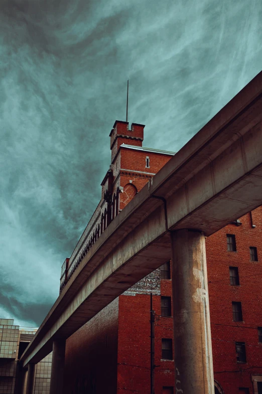 a view from under the road of an old building with a bridge