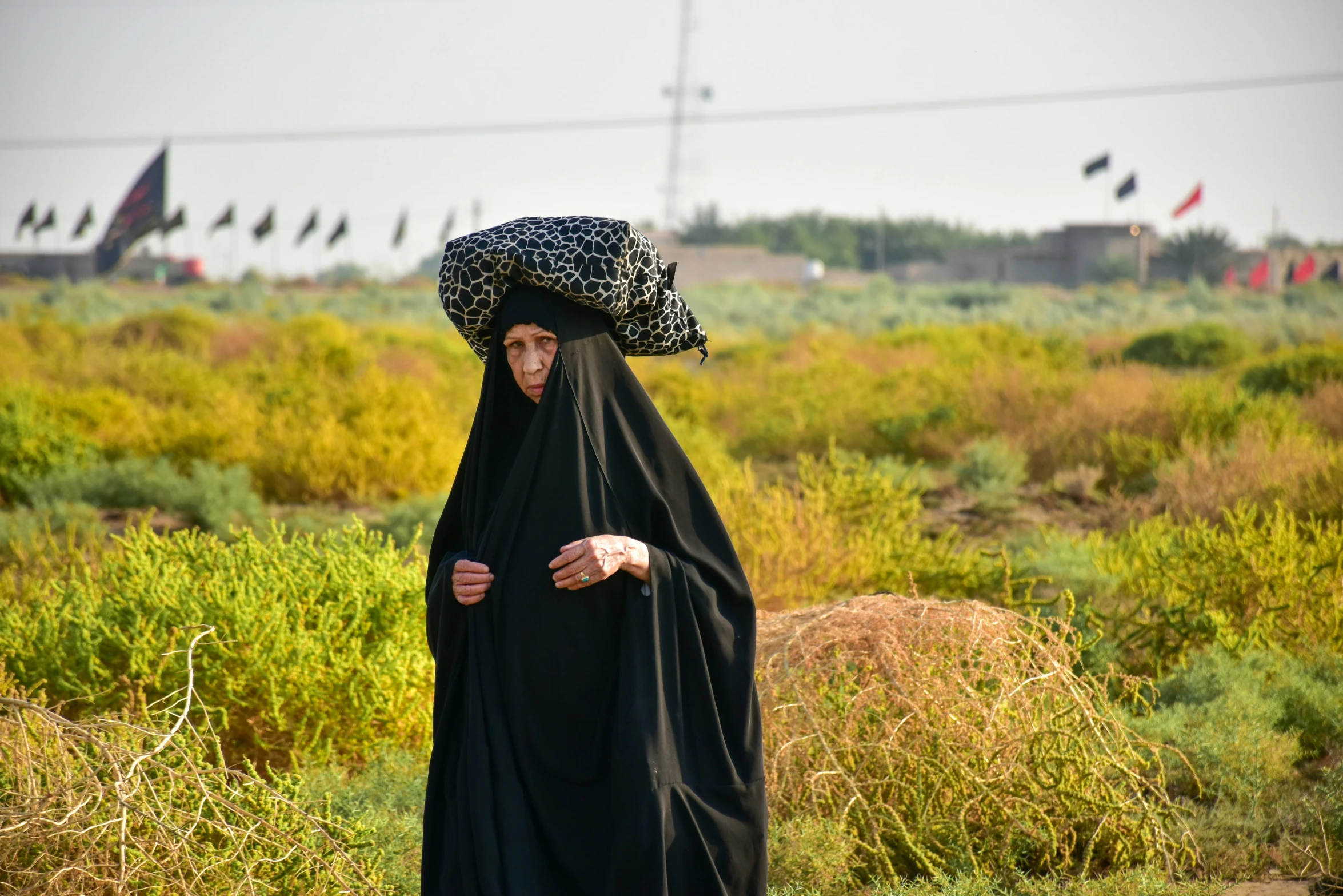 a woman is wearing a black dress with a patterned head cover on it