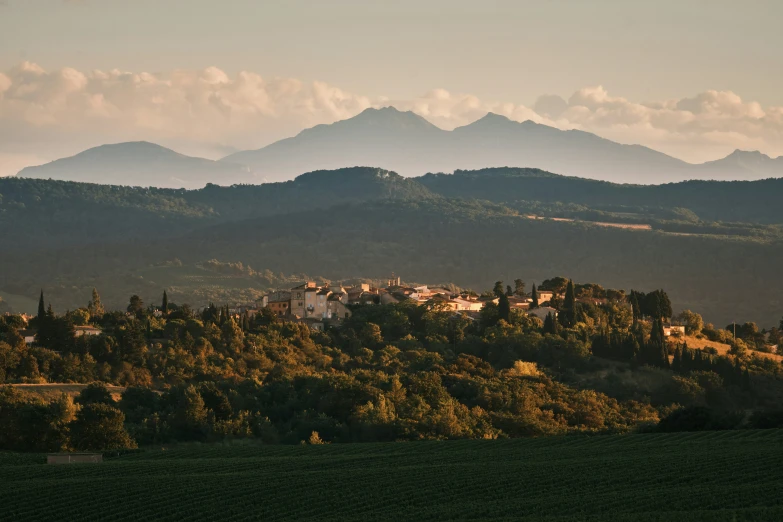 a large hill with some houses and mountains in the background