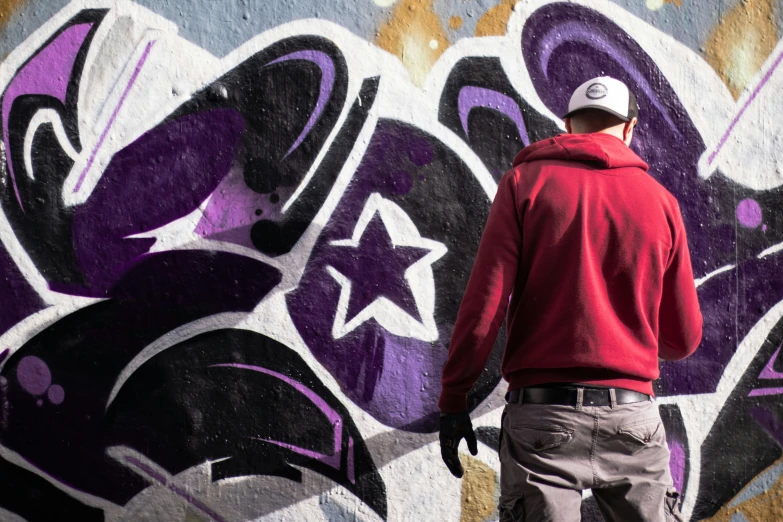 man stands in front of a wall with many different graffiti