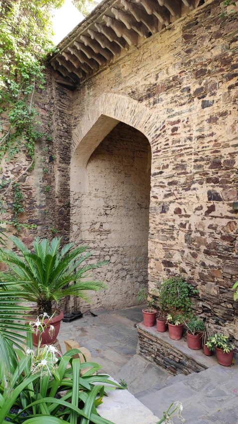 an entry to a brick building surrounded by lots of plants