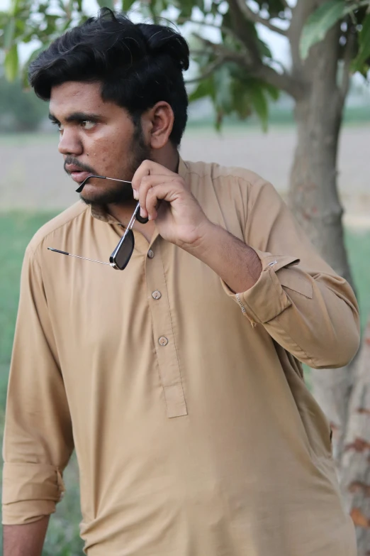 a man in an orange shirt talking on his cellphone