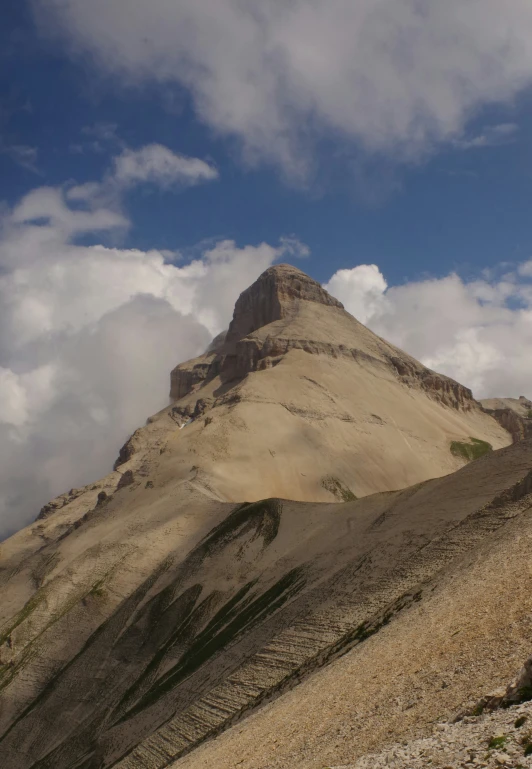 a very tall, steep rock hill with a blue sky in the background