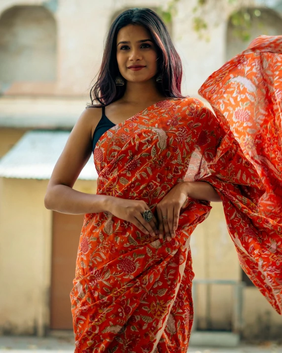a woman with an orange patterned sari holding a shawl