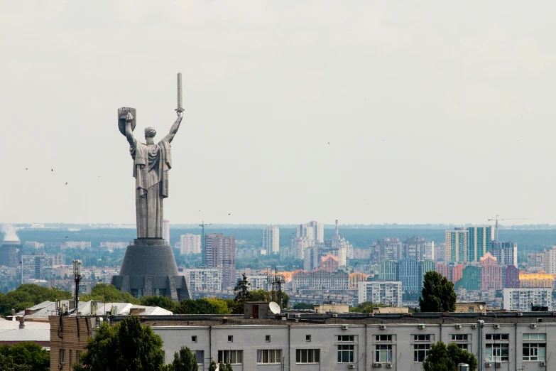 a statue that looks like an old woman stands in front of the backdrop of large buildings