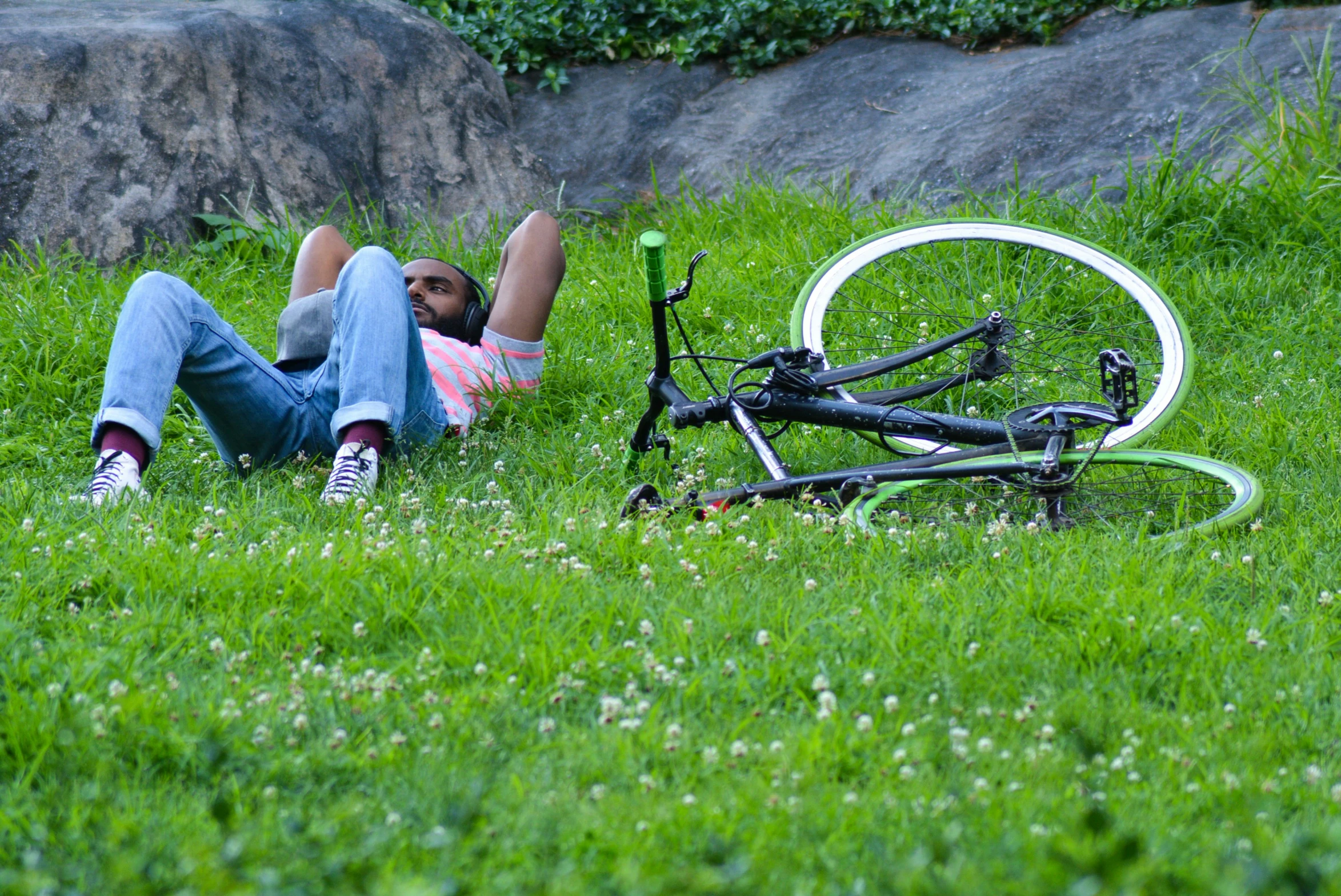 the boy is laying down in the grass next to the broken bike