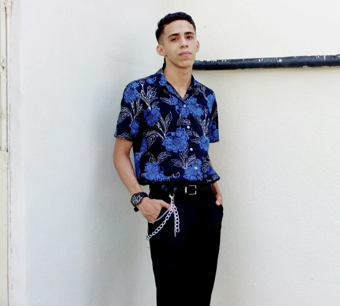 a young man in a blue shirt standing on a cement wall