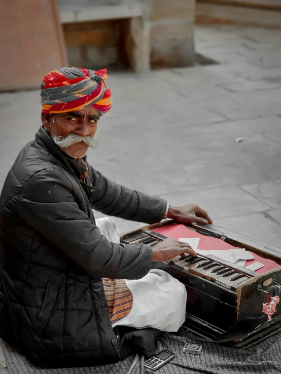 an old indian man plays the organ on the street