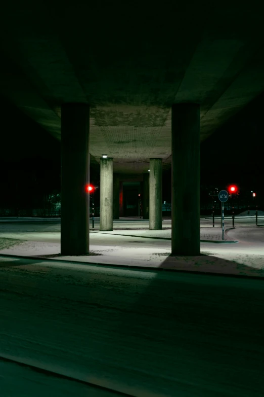 an empty space underneath a highway with traffic lights on