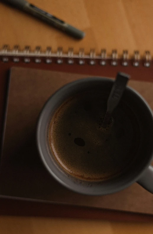 a cup of coffee sits next to a spiral - bound notebook